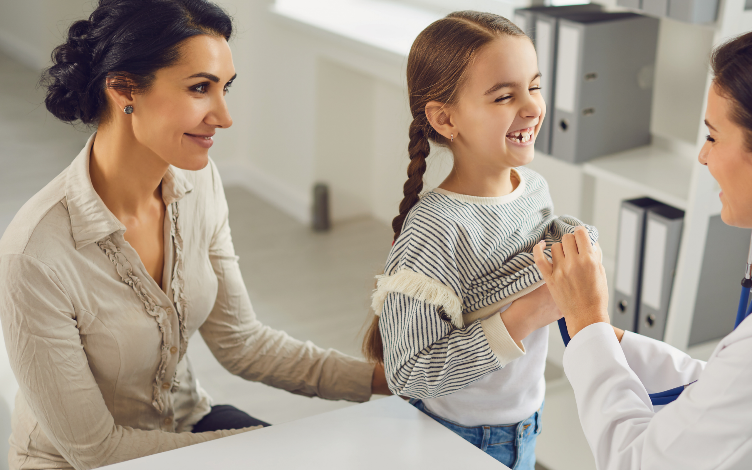 Mamă și fetiță în timpul unei consultații medicale, imagine ilustrativă pentru evaluarea pubertății precoce la copii.